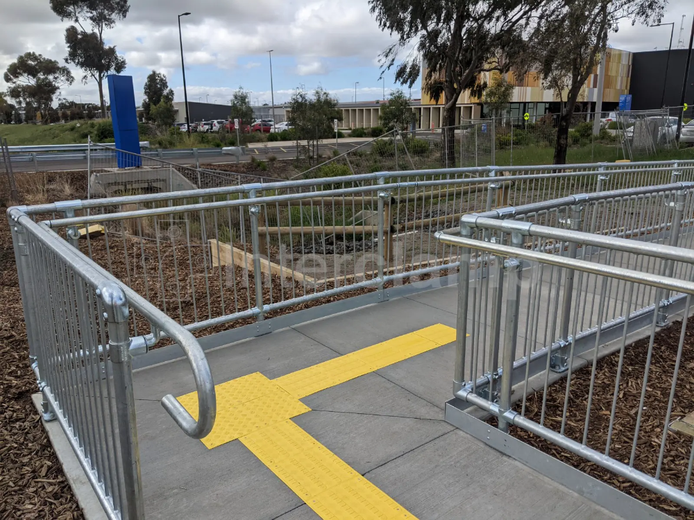 Interclamp pedestrian barriers and DDA assist rail installed at a bus stop, providing both safety and accessibility for pedestrians.